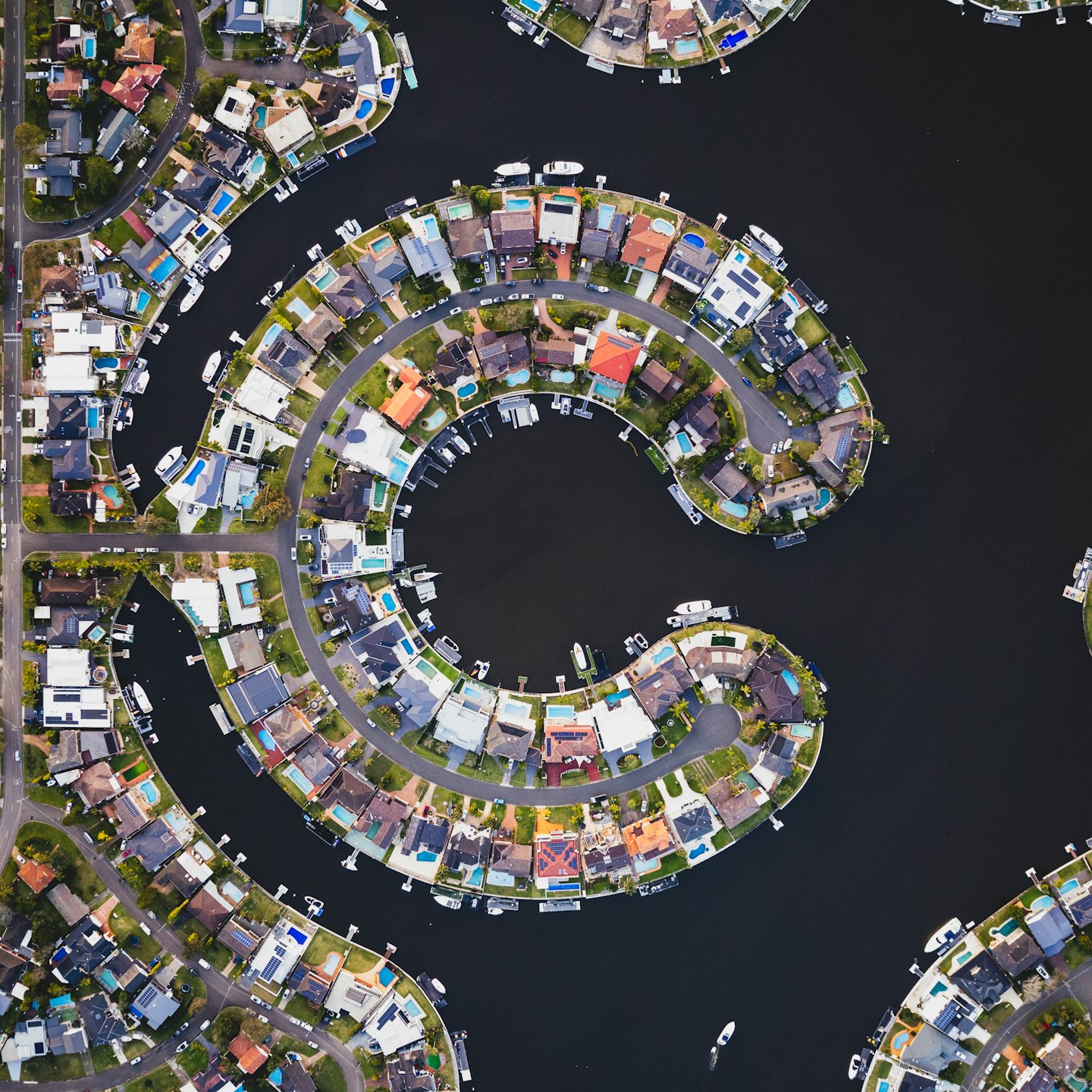 Residential houses with pools sit along suburban waterfront canals.