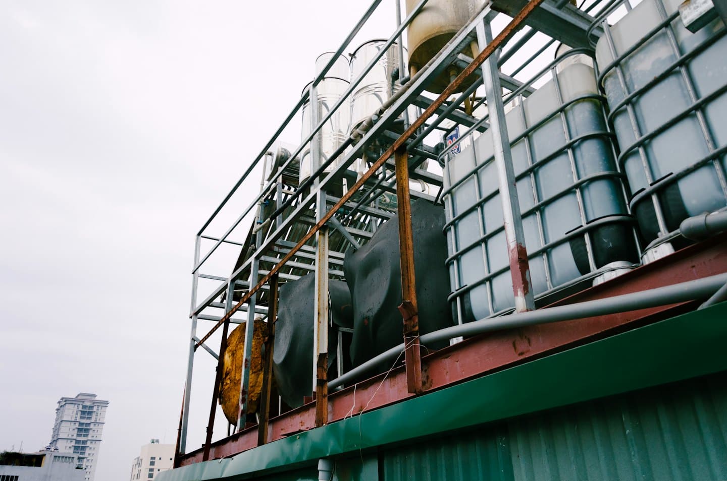 Industrial water tanks on a rooftop under a grey sky.